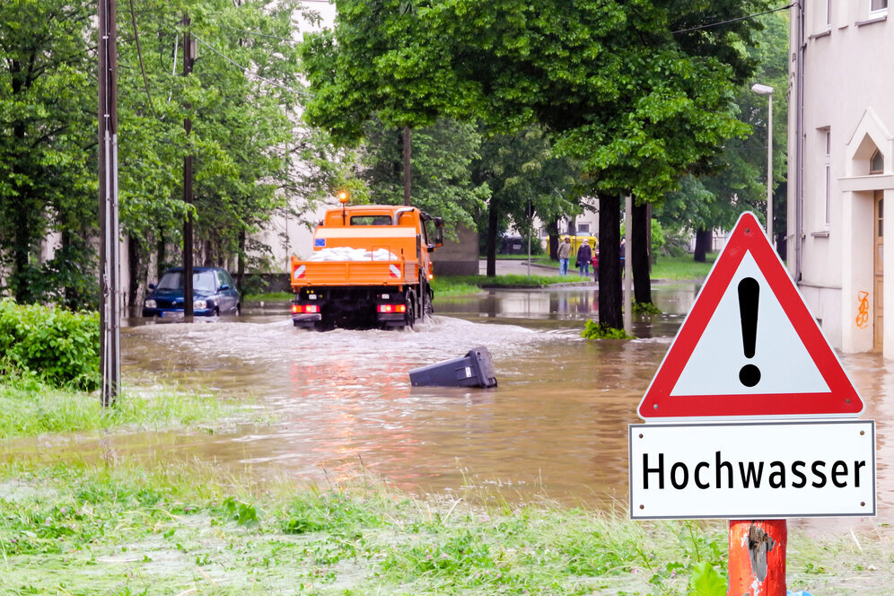 Hochwasser in der Stadt, Bauhoffahrzeug fährt durch überflutete Straßen