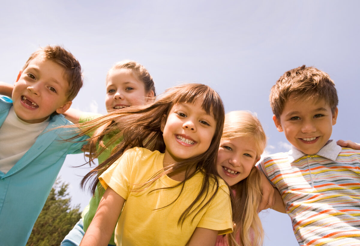 Gruppe Kinder Arm in Arm schauen in die Kamera die vom Boden ein Foto macht