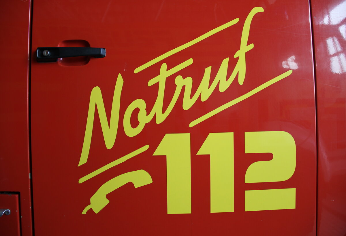 Notruf 112 an der Tür eines Feuerwehrautos